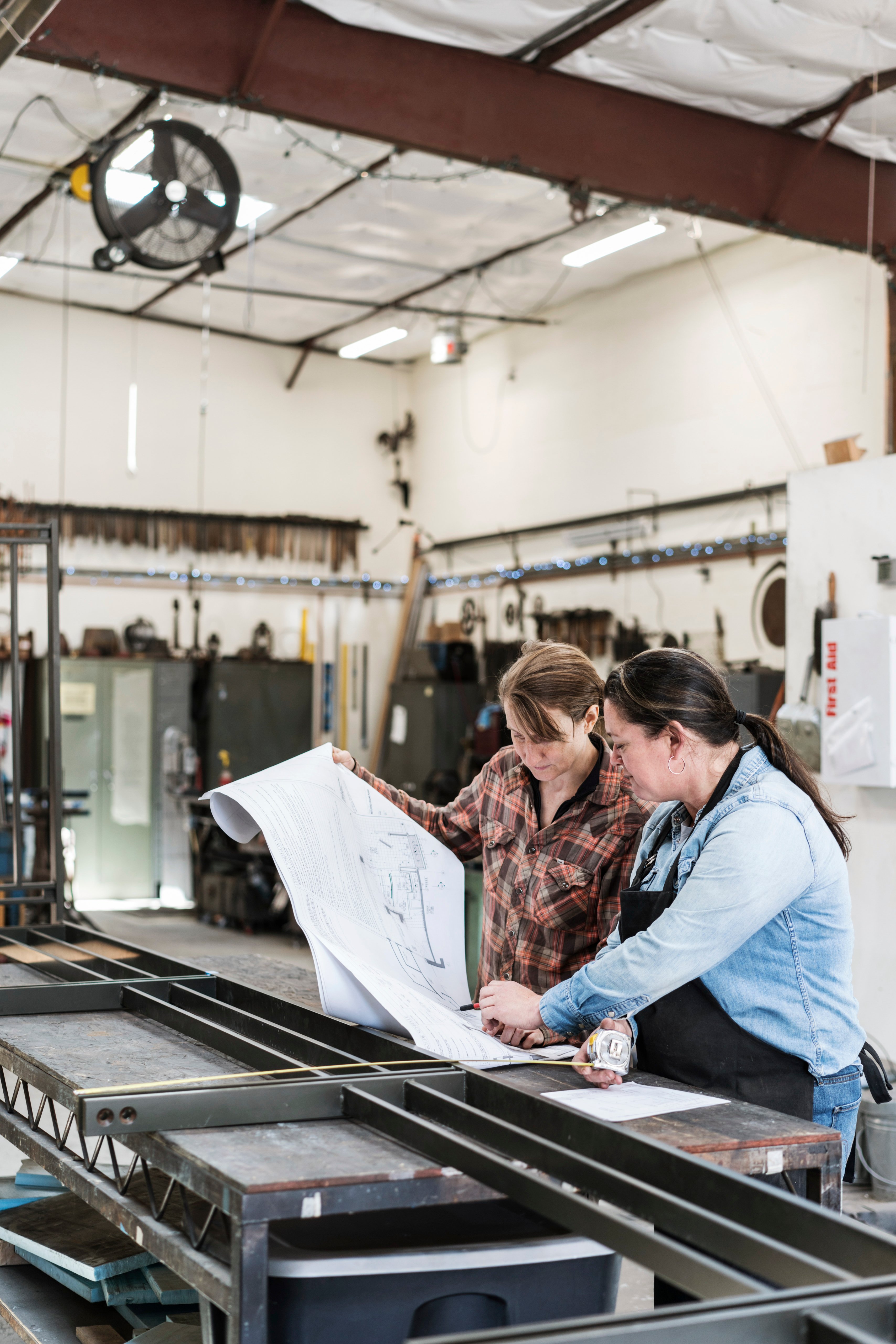 two-women-standing-at-workbench-in-a-metal-worksho-2025-04-03-13-28-08-utc